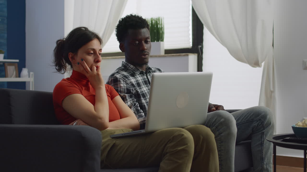 Married couple of interracial partners looking at laptop