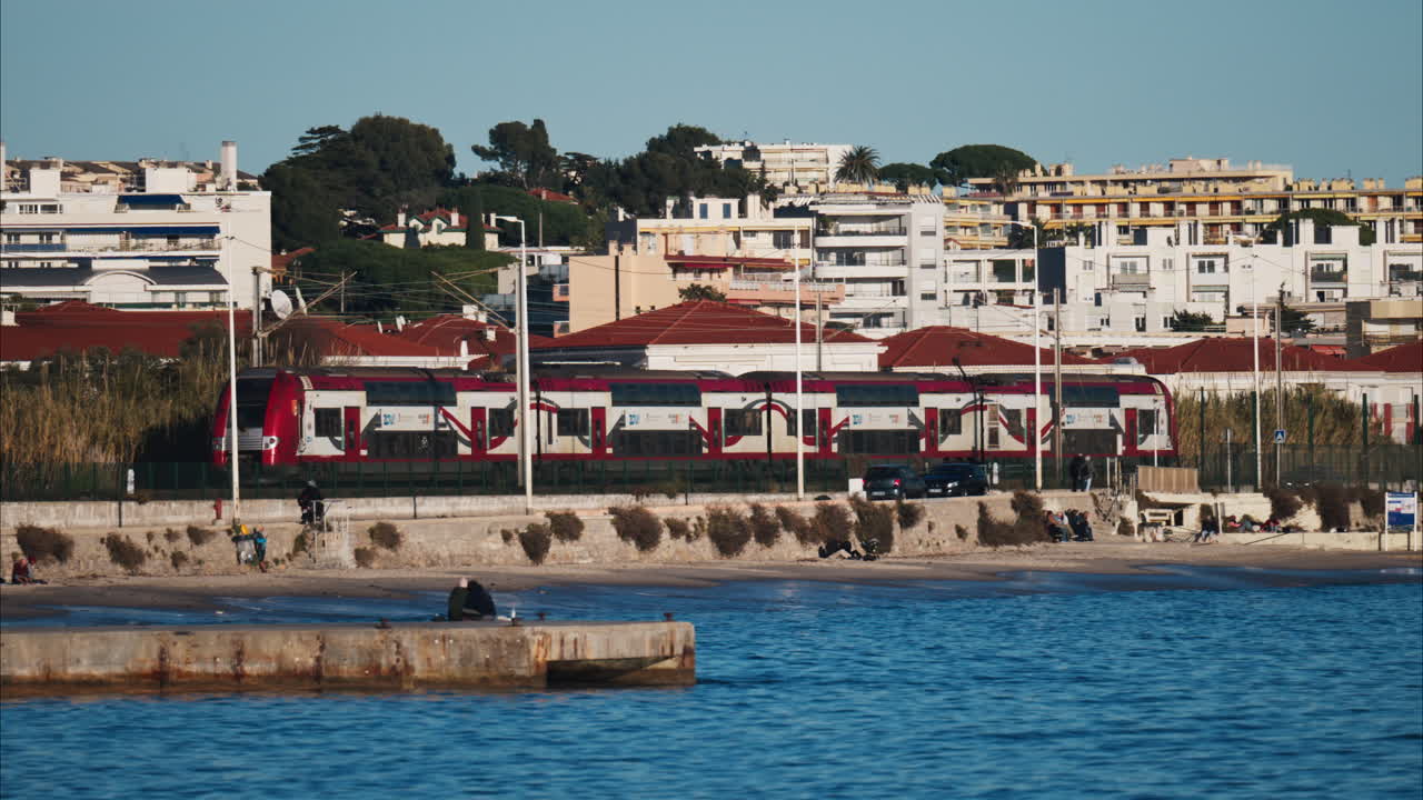 Juan-les-Pins, France - January 25, 2025: Red train moving on the rails in Antibes, on the coast of the sea