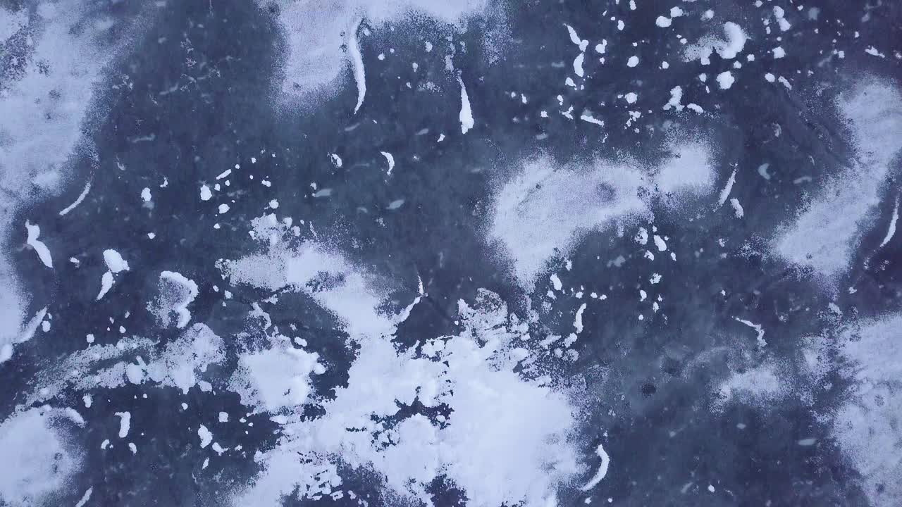 vista aérea de pájaro del lago congelado liepaja durante el invierno, hielo azul con grietas, islas secas de juncos amarillentos, día de invierno nublado, gran tiro de drones avanzando