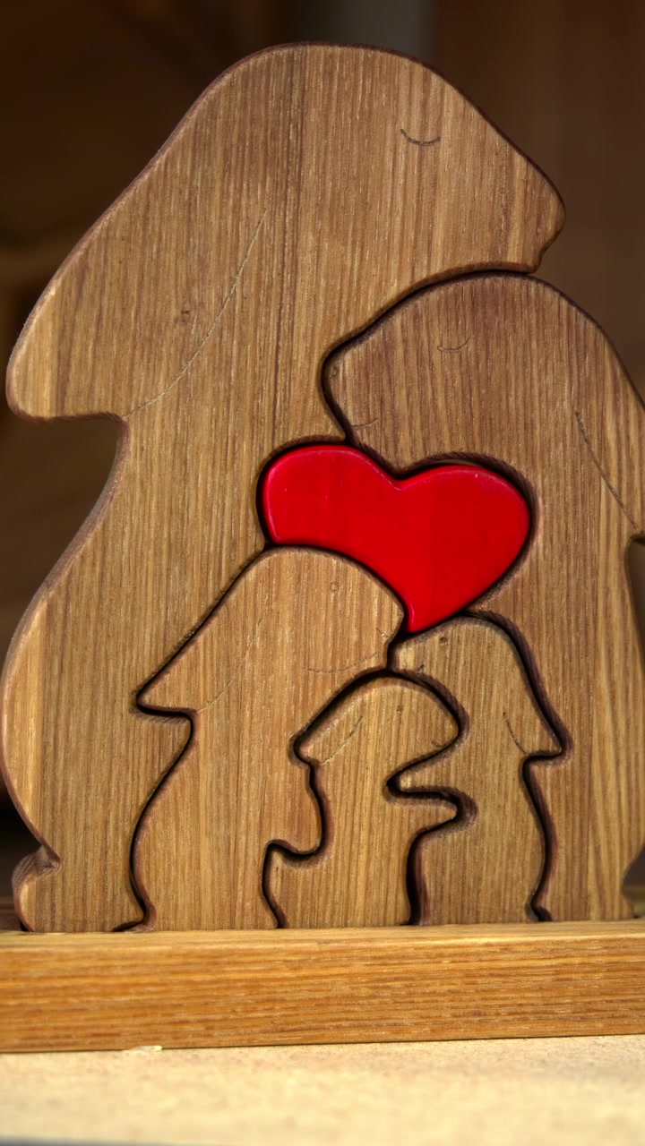 Puzzle familiare in legno con cuore rosso, figure a silhouette fatte a mano su uno scaffale rustico da officina, illuminazione calda direzionale.