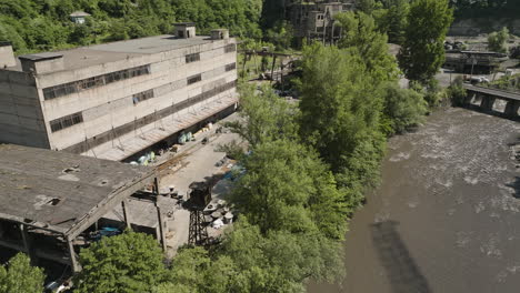 abandoned factory complex warehouse on river shore, chiatura, georgia