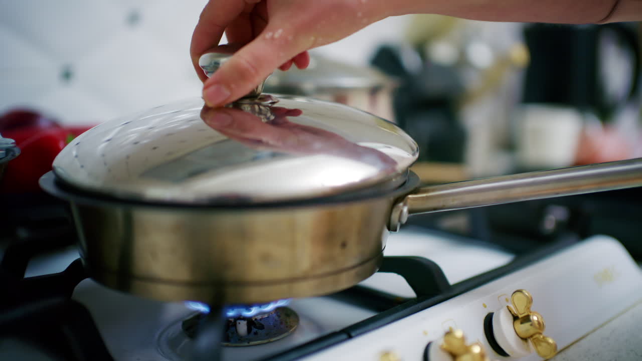 Close up of a pot on a gas stove with a visible blue flame heating from below