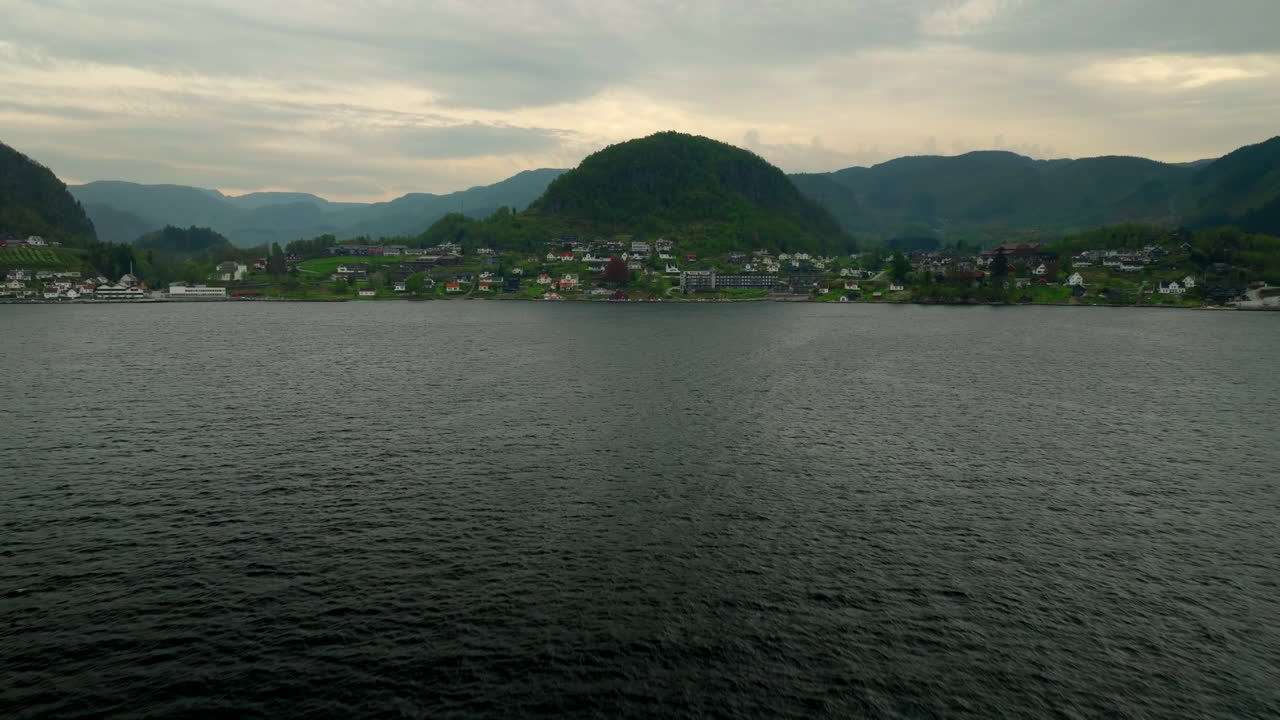 Drone flying over sea towards Hjelmeland town, mountain landscape in Rogaland, Norway. Aerial forward