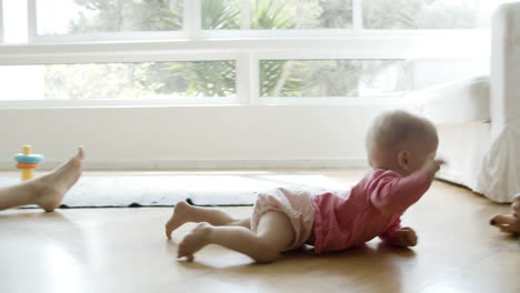 cute baby crawling on floor from mom to dad and grasping phone