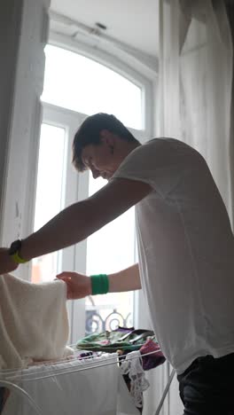person drying clothes by the window