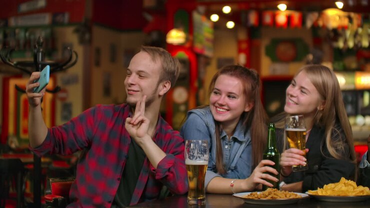Un uomo e due persone scattano un selfie divertente in un bar.