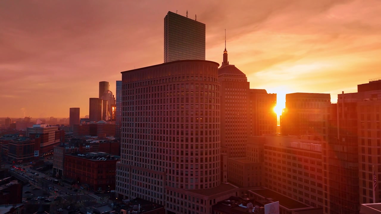 Arquitectura del centro de Boston con el telón de fondo de un cielo naranja. Vuelo de dron sobre la animada ciudad al atardecer