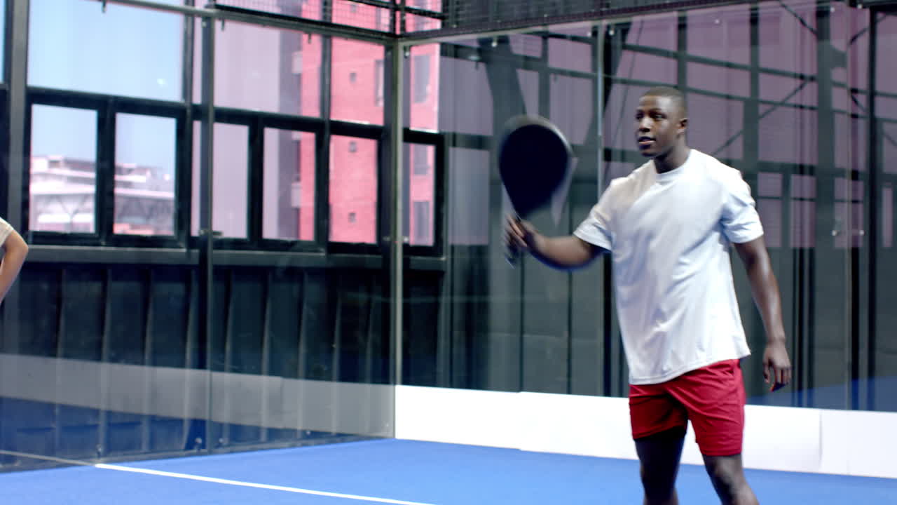 Athlete holding padel racket on indoor court, preparing for intense match