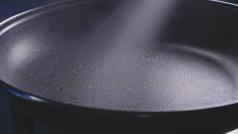 spraying oil on frying pan, close up view