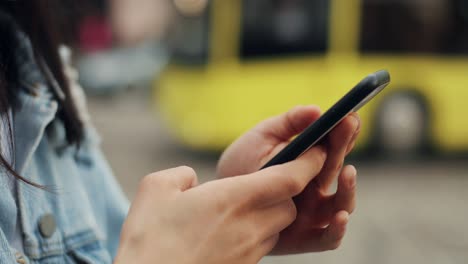 cierre de las manos femeninas escribiendo y enviando un mensaje de texto en el teléfono inteligente afuera en el centro de la ciudad y luego la cámara se mueve hacia la cara bonita y alegre de una mujer