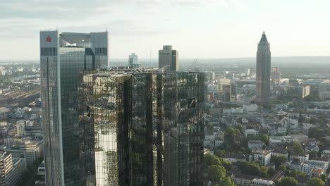 AERIAL:-Flight-towards-Frankfurt-am-Main,-Germany-Skyscraper-reflecting-in-Sunlight-in-June-2020