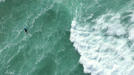 vista superior aérea de 4k de un surfista remando hacia las aguas profundas del océano con su tabla de surf en australia