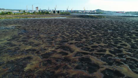 Toxic-black-puddles-of-mud-and-tar-remain-in-asphalt-lake,-aerial-dolly