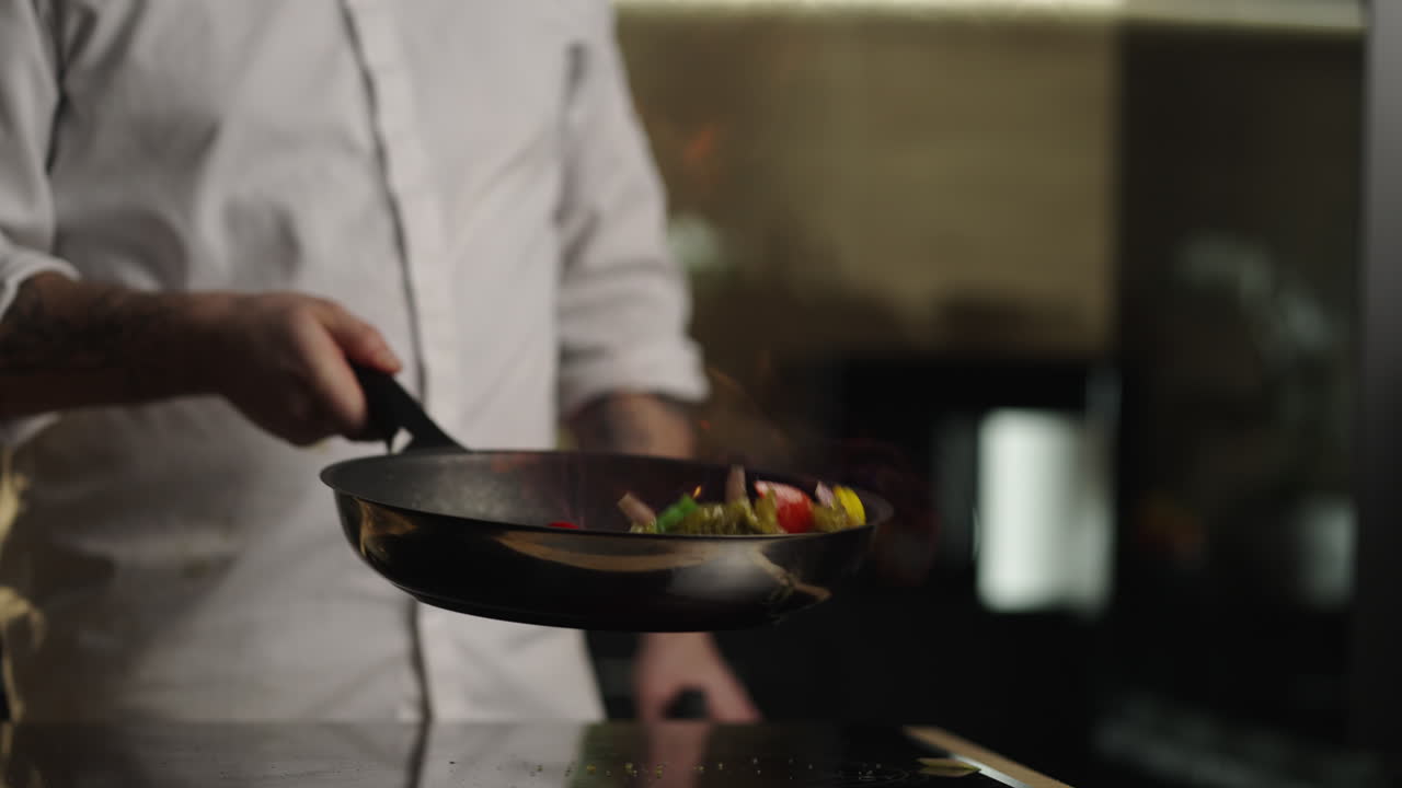 Chef cooking stir-fry in frying pan