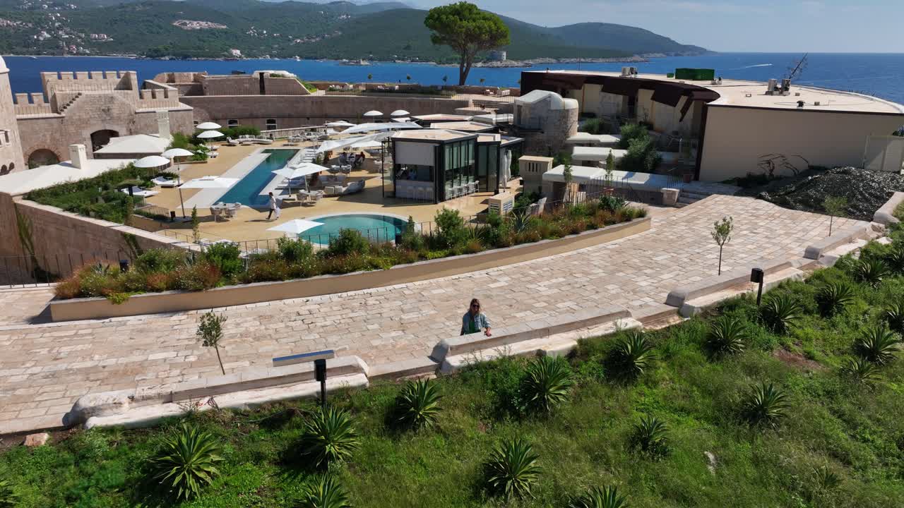 Aerial zoom-out of Mamula Island resort surrounded by clear sea and sunshine