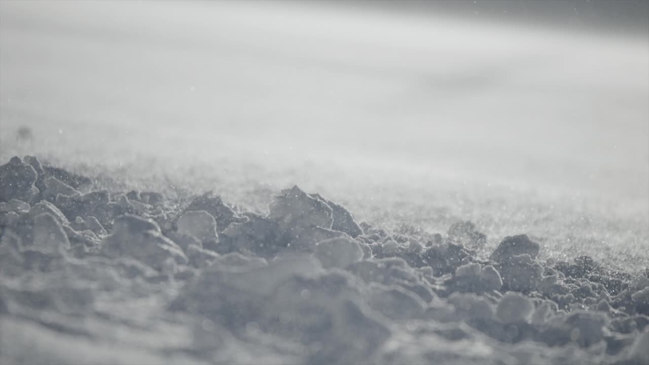 Ground Shot Of Snowflakes Moving Softly By Wind Over Snowy Surface