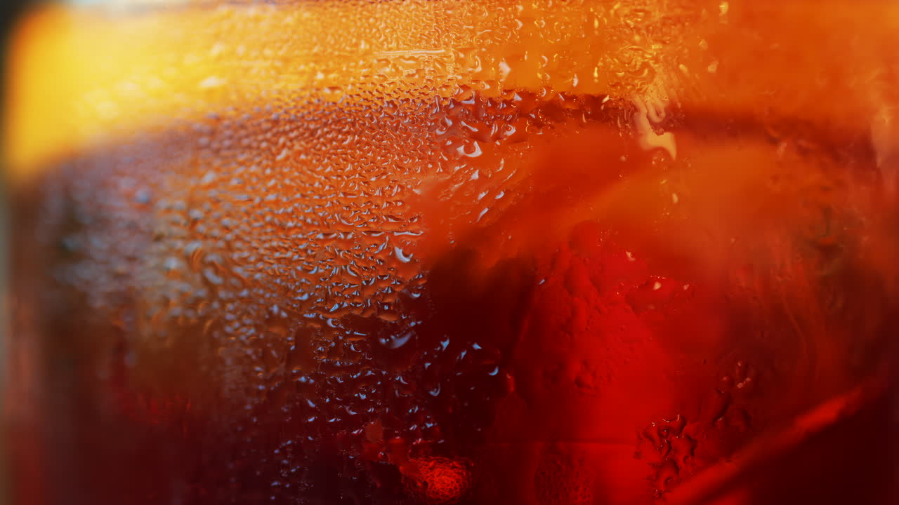 Close up of a Negroni cocktail with orange slice and ice cubes on a wooden table