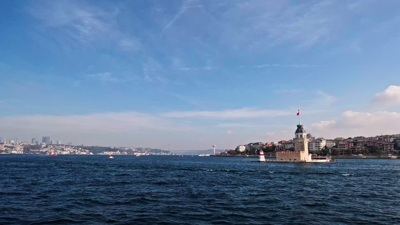 High-quality 4K footage capturing the beauty of the Maiden's Tower surrounded by the blue waters of the Bosphorus. The background features the urban coastline of Uskudar and distant city silhouette