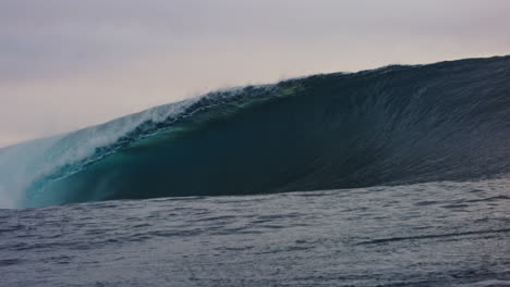 strong heavy ocean wave crashes in green shimmering barrel, view from in water