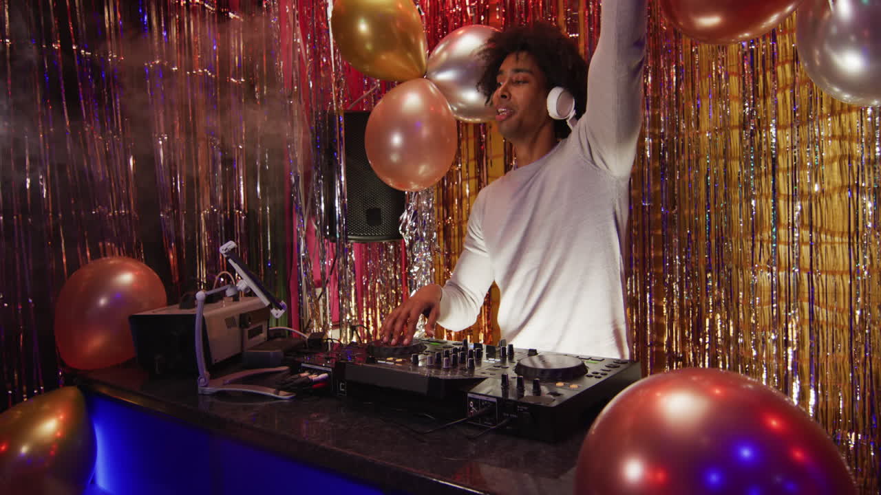 Video of happy african american male dj playing music, dancing and using microphone at a nightclub