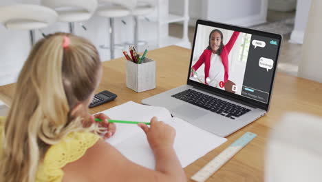 schoolgirl using laptop for online lesson at home, with her colleague and web chat on screen