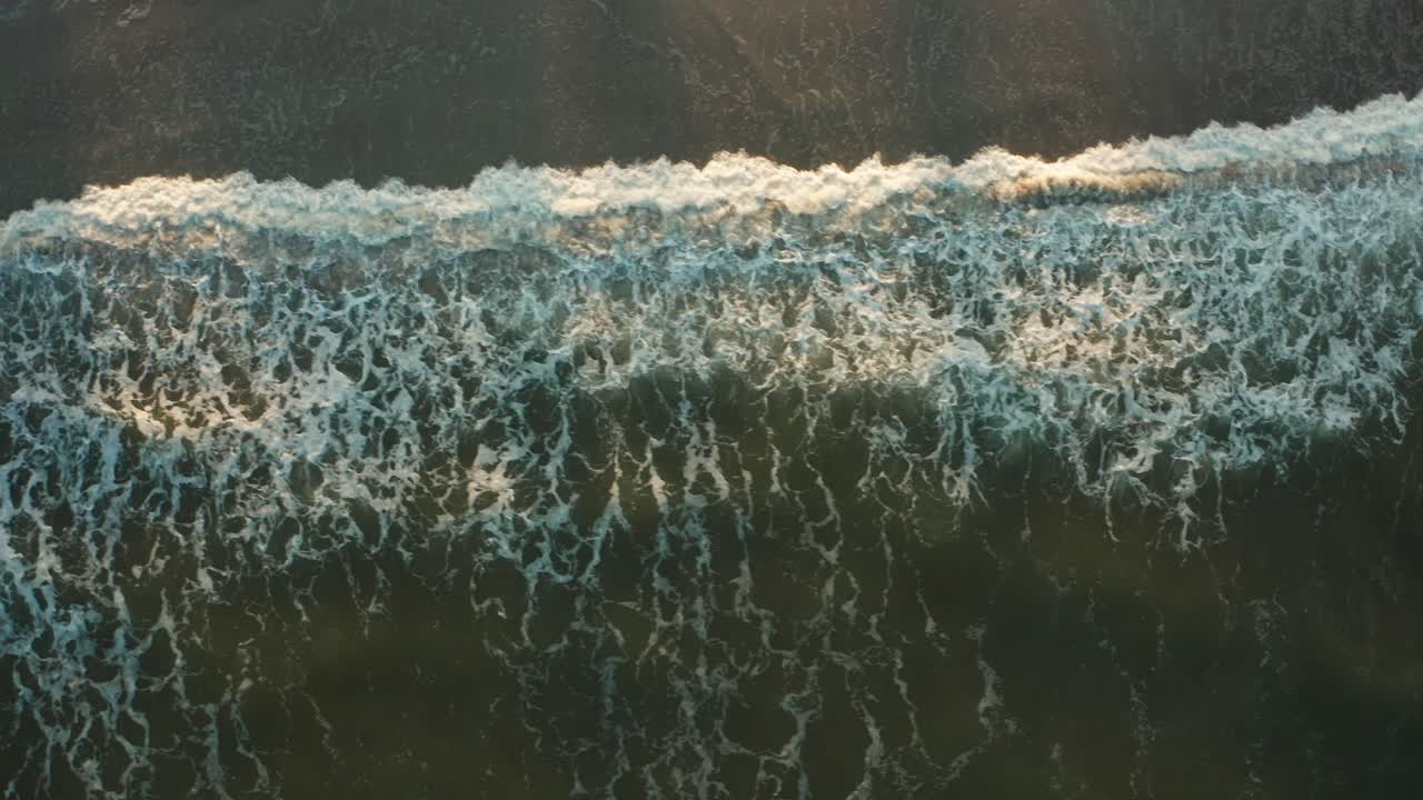 Aerial top down, wave tide crashing onto beach shore