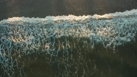 aerial top down, wave tide crashing onto beach shore