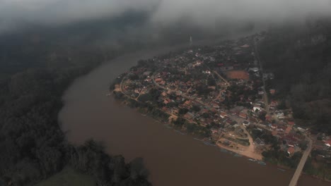 Wide-shot-of-Nong-Khiaw-Laos-with-low-clouds-during-sunrise,-aerial