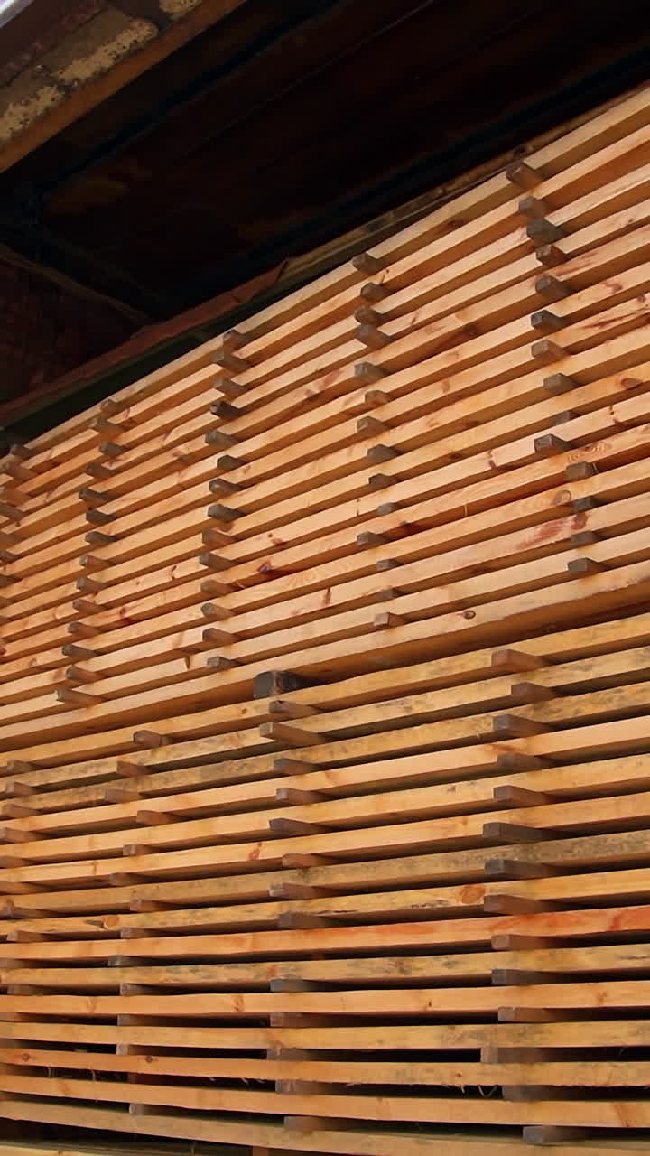 Wooden planks piled in a warehouse up to the top. Timber prepared and stored for modern door production. Vertical video