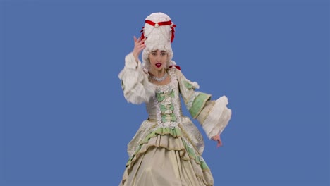 portrait of courtier lady in white vintage lace dress and wig is dancing merrily. young woman posing in studio with blue screen background. slow motion