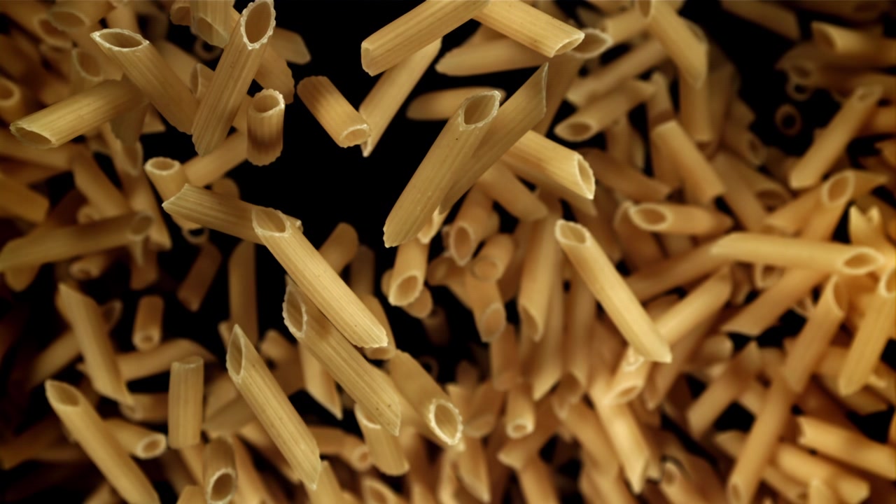 Rallentatore di pasta penne secca che cade su sfondo nero