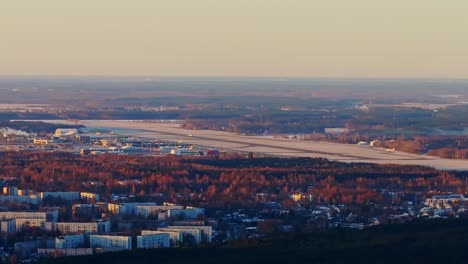 plane takes off at dawn over riga airport, seen from afar glowing spring sunrise