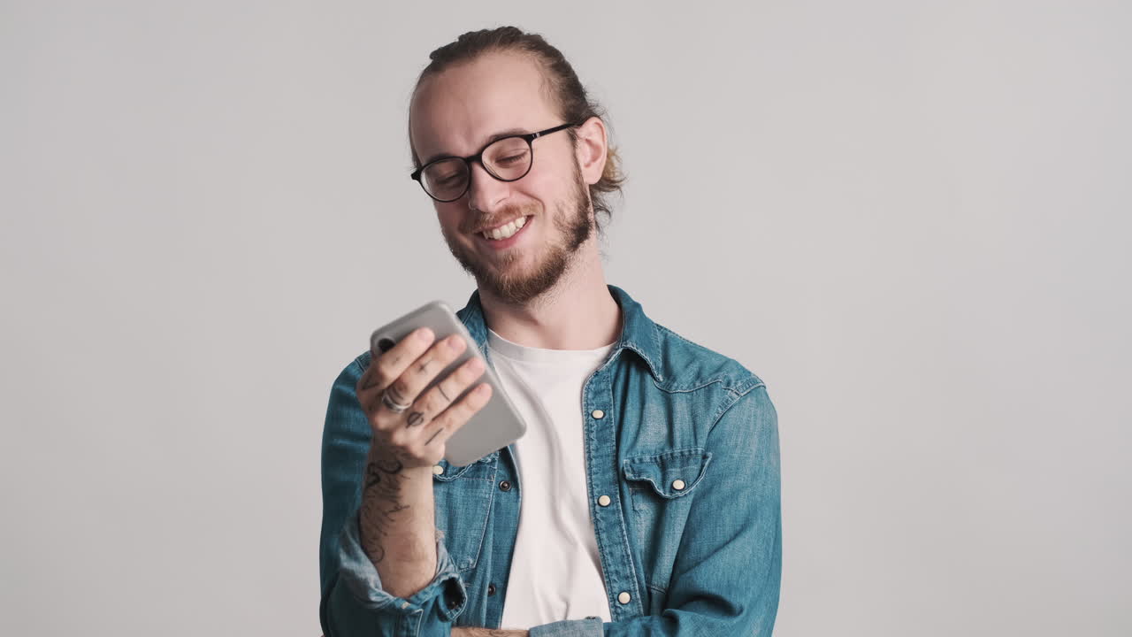joven caucásico usando el teléfono inteligente en la cámara.