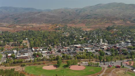 Aerial-view-of-Downtown-Steamboat-Springs,-two-baseball-fields,-and-a-mountain-range