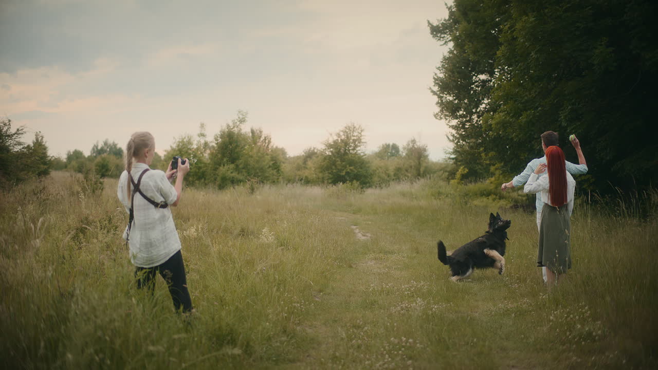 A couple and their dog enjoy a day in the field while a photographer captures the moment