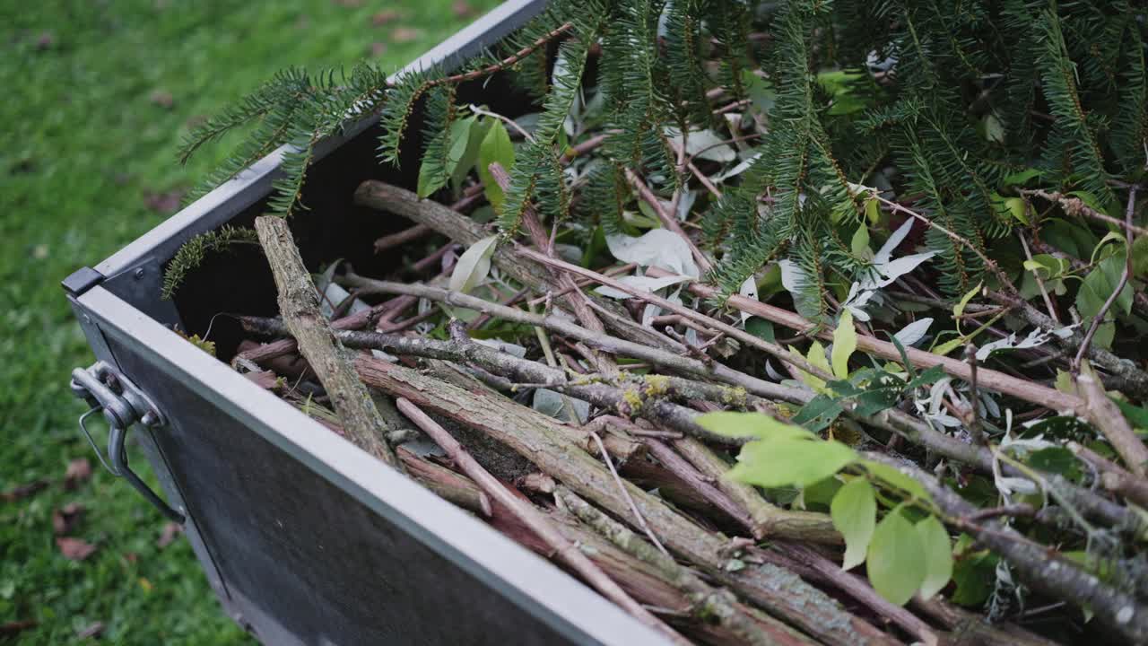 Elevated view of a trailer in a traditional German garden, filled with tree and shrub cuttings, highlighting seasonal garden cleanup and natural textures