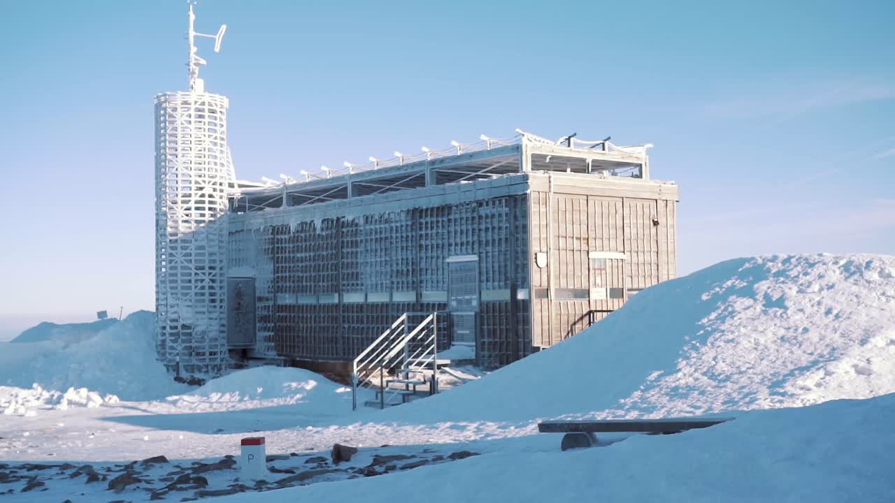 Frozen and snowy weather station on top of mountain on sunny day, winter scene