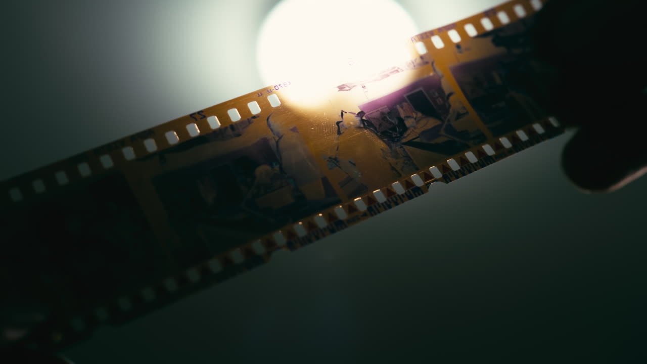 35mm film strip held against a bright light source. Vintage analog photography concept with retro cinema feel, perfect for projects about nostalgia, creativity, and the art of film