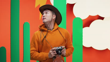 man with camera in front of a cactus wall