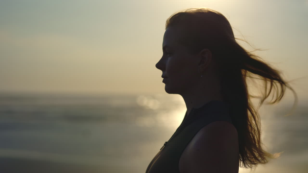 Woman in silhouette at the beach at sunset