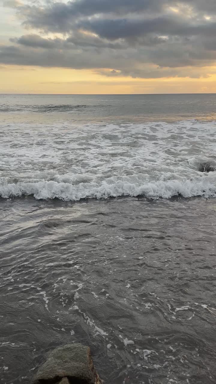 Onde oceaniche tranquille che si infrangono sulla riva al tramonto
