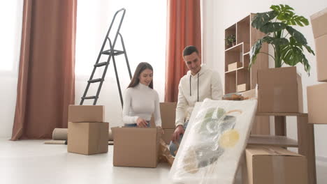 feliz pareja mudándose de casa empacando sus pertenencias