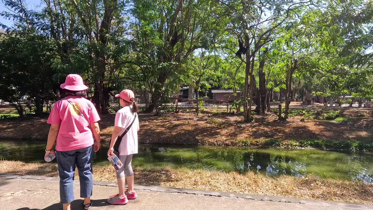 Two people walking near a scenic pond