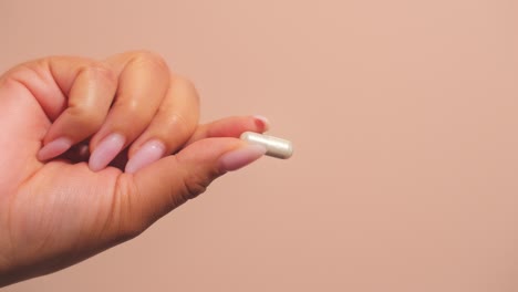 la mano de la mujer sostiene una cápsula o píldora, que simboliza el bienestar