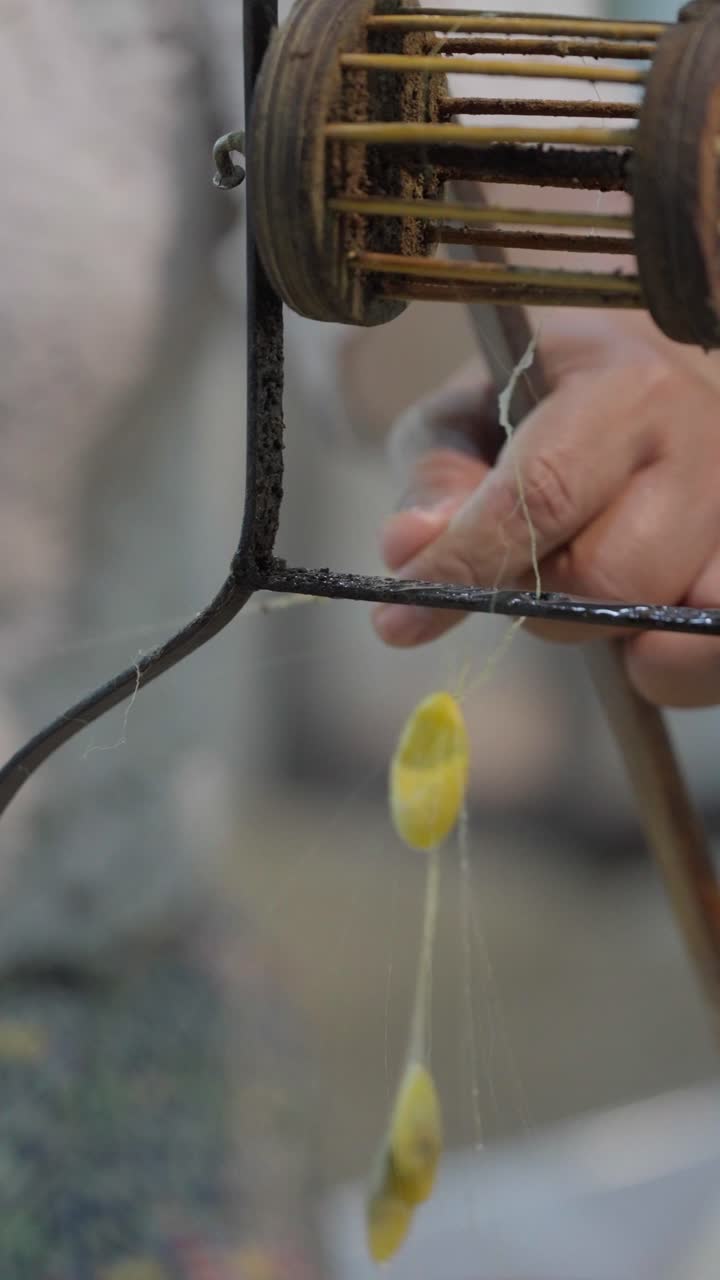 Slow motion closeup hand removing a spent cocoon from silk reeling process in Thailand showing delicate thread separation in traditional sericulture