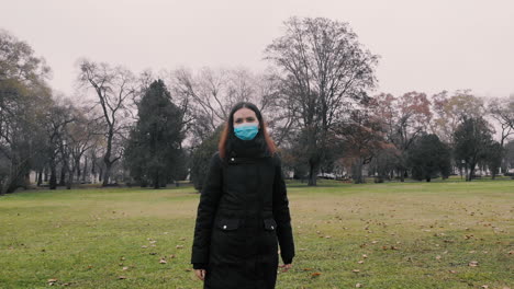 front view of a young woman walking alone on a green field, park on a cloudy day