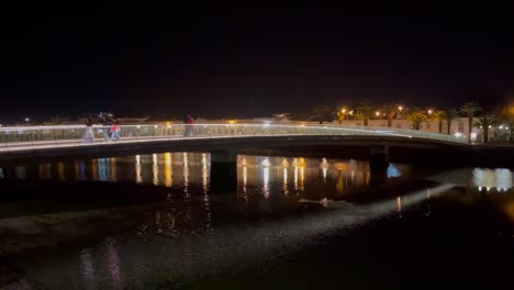 puente peatonal bellamente iluminado sobre el río galao en tavira portugal, en una cálida noche de primavera