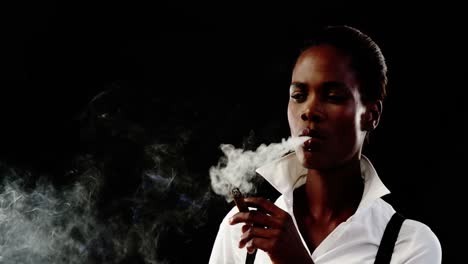 androgynous man smoking cigar against black background