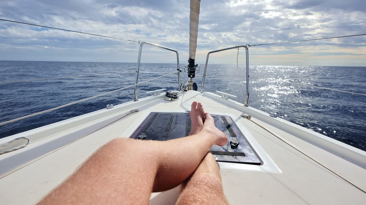 Close sea journey moment as man chills on sailboat deck, clear blue sky light