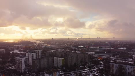 Puesta-De-Sol-Dorada-Y-Nevadas-Ligeras-Sobre-Los-Suburbios-De-La-Ciudad-De-Riga,-Vista-Aérea